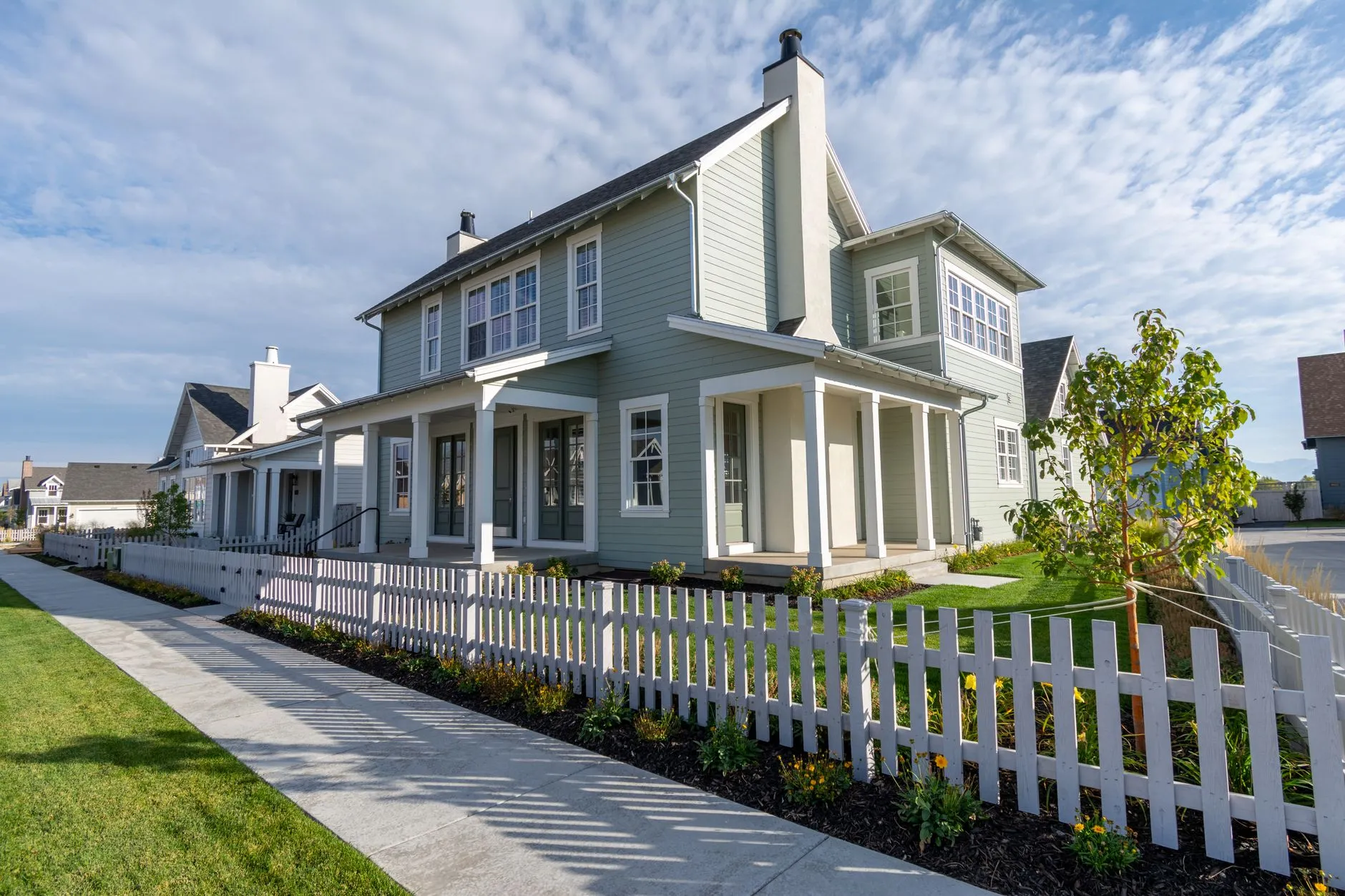 A white picket fence running along the front of a suburban house.