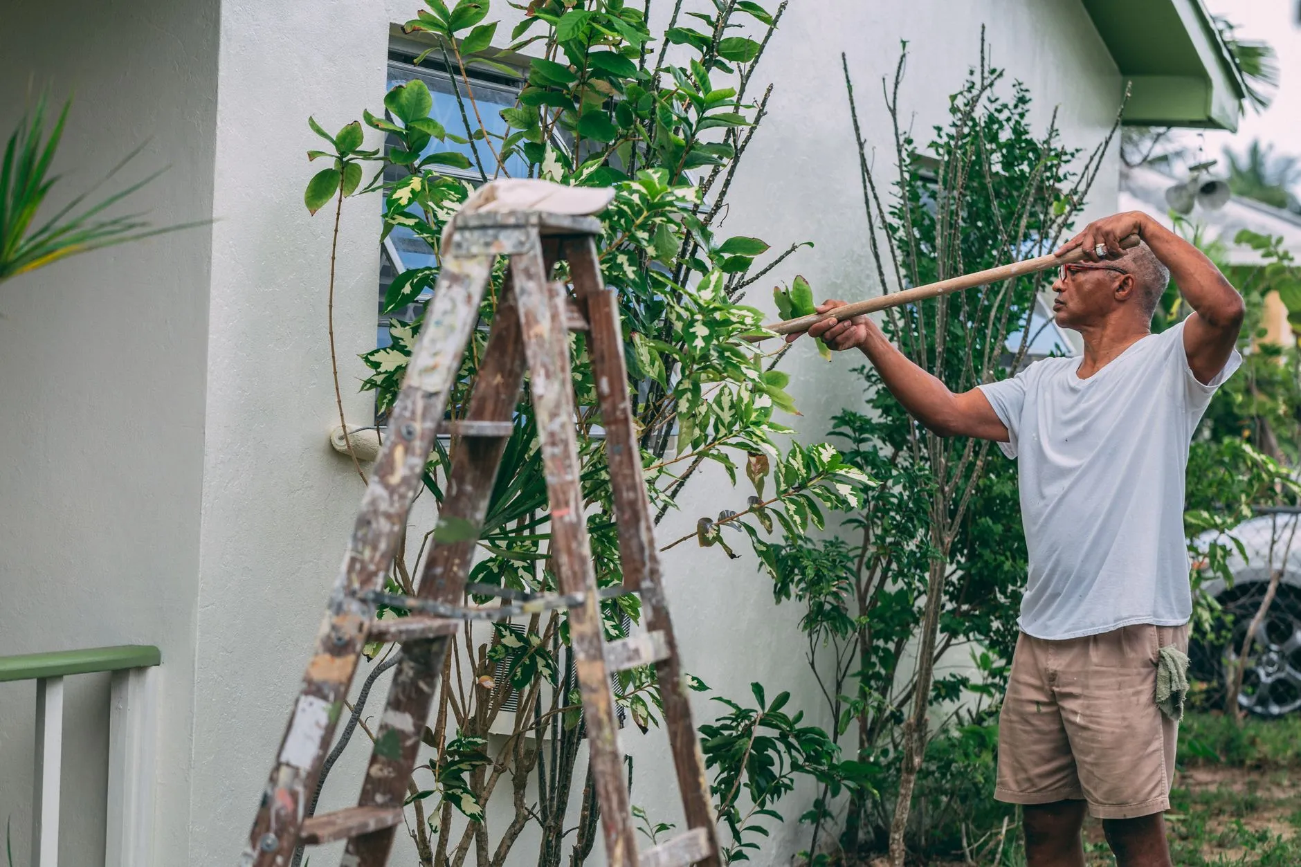 Someone painting the exterior wall of a house with a roller.